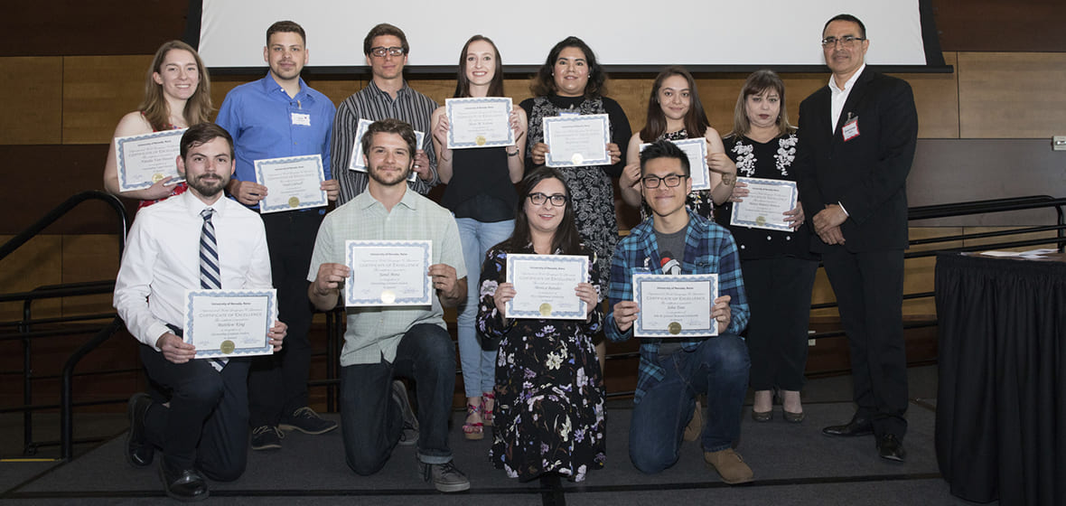 Award winners hold up certificates on stage during 2018 awards ceremony.