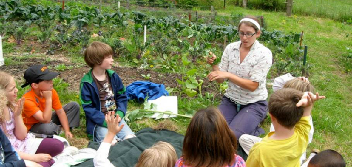 A student teaches a group of children about plants