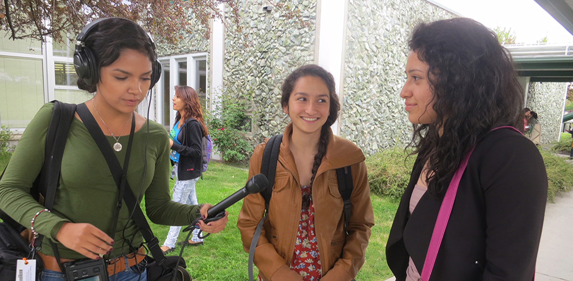 Student records two students using a microphone outdoors.