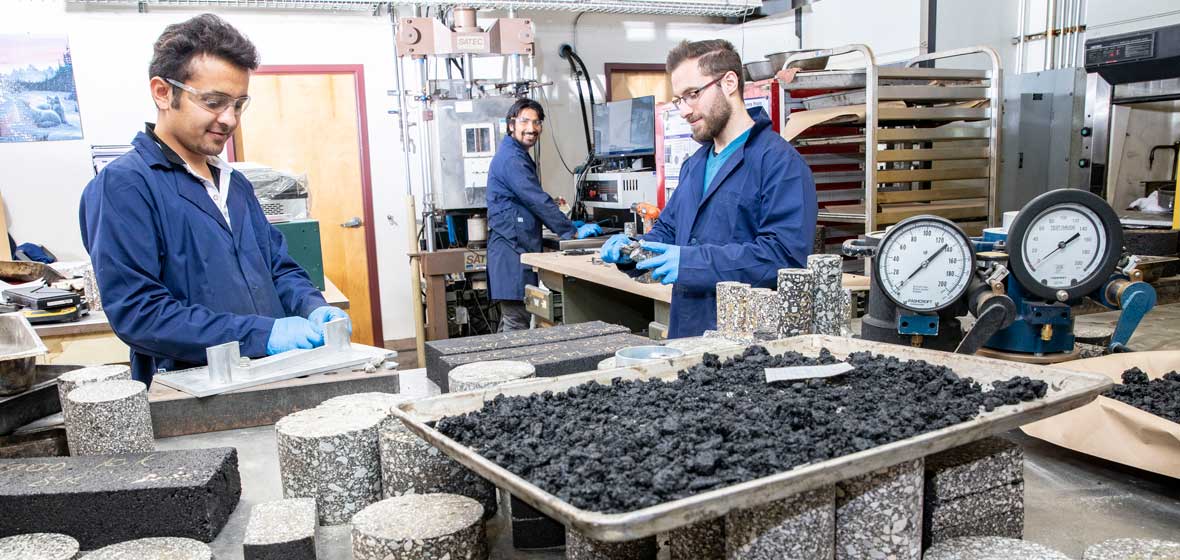  Three men working in a pavement lab.