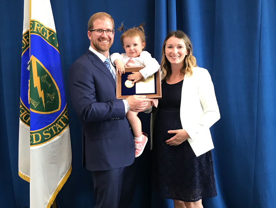 Rick Kraus poses for a photo with his young daughter and wife on the stage at the PECASE awards ceremony