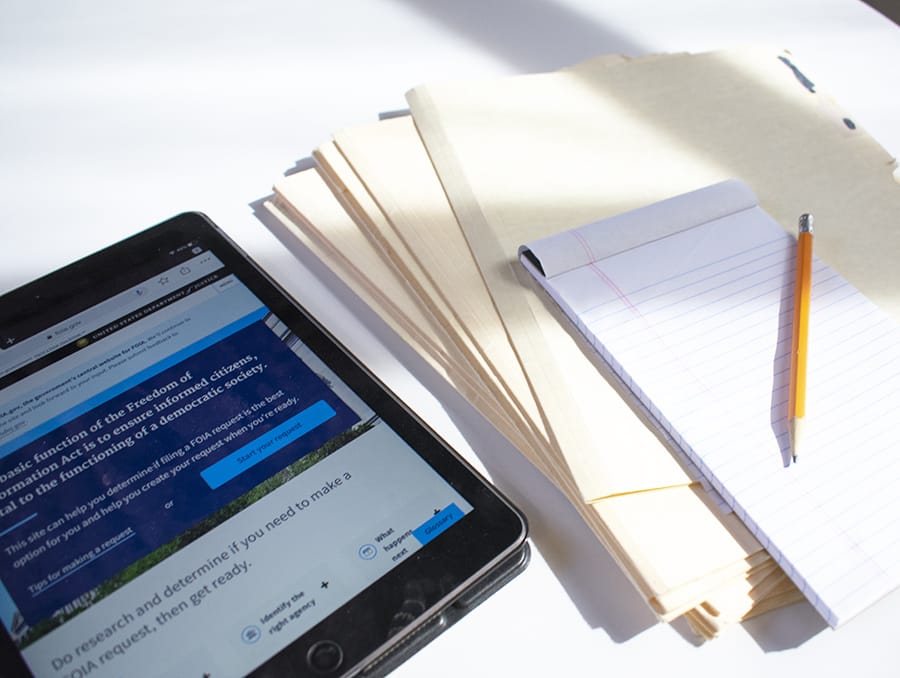 A table with an iPad, files and a notebook sitting on it.