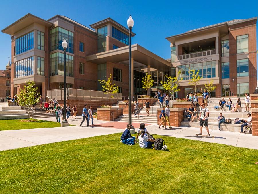 Pennington Student Achievement Center during a typical sunny day with students walking by and sitting on the lawn and various benches