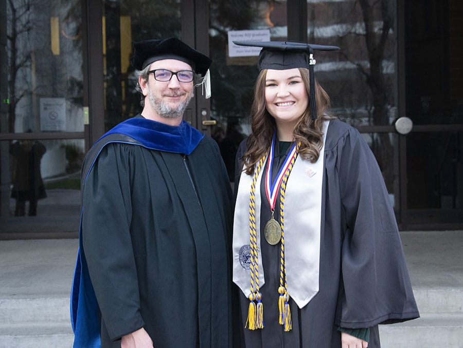 A faculty member and student pose in front of the Reynolds School of Journalism