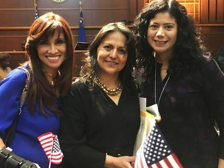 Lizeth Ramirez-Barroeta in a courtroom holding a U.S. flag and flanked by two of her coworkers.