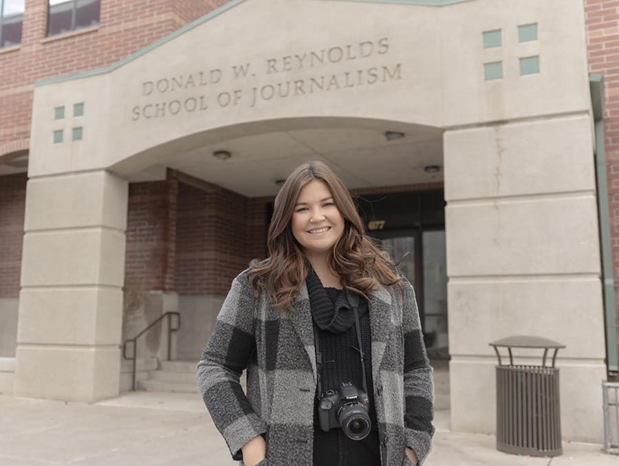 A student stands in front of the Reynolds School of Journalism