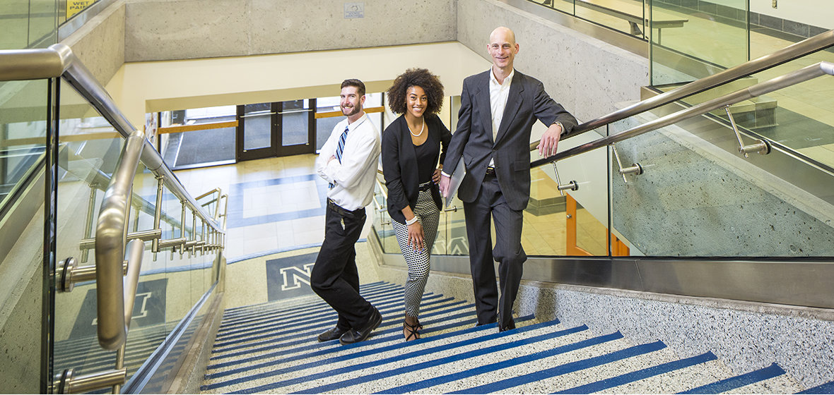 Three College of Business students on the stairs in the Ansari Business Building.