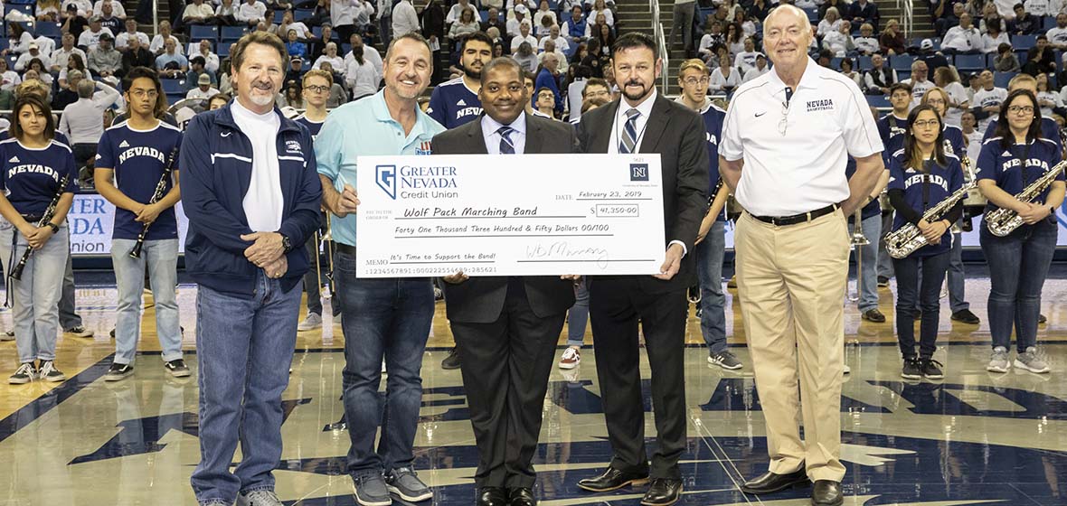 Five men stand on a basketball court with a large check held in the middle.