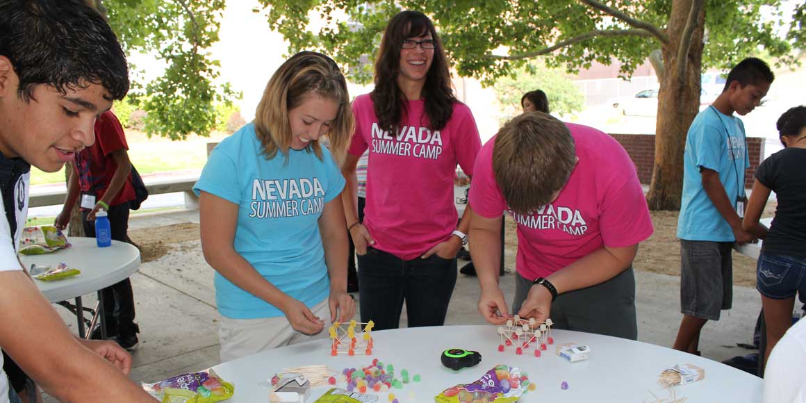 People gathered around a table and creating structures from candy.