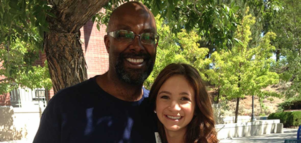 A man and a woman hug in front of a tree. 