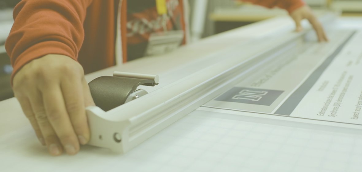 @One service desk worker trims a large scale poster on a large scale paper trimmer