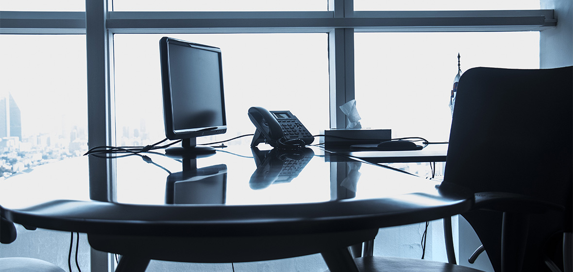 A stock image of an office with a monitor, desk and phone. 