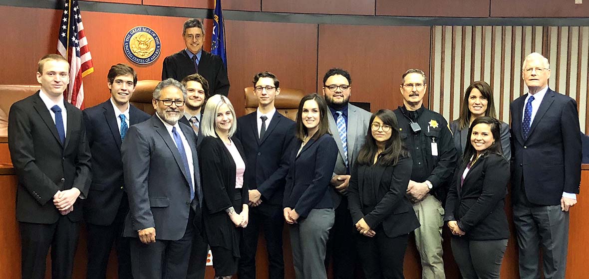Mock trial group poses in courtroom