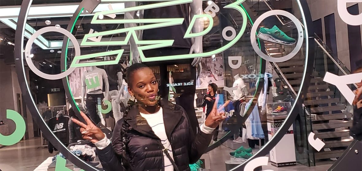 Woman poses inside a New Balance shoe store.