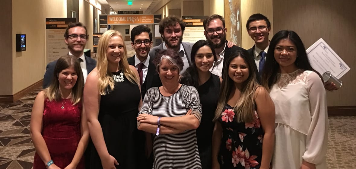 Students and a professor pose indoors.