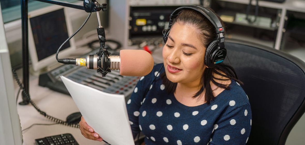 Woman speaks into a microphone indoors.