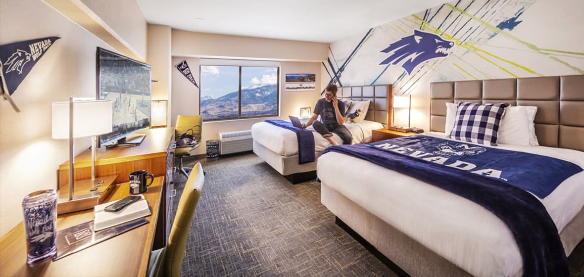 A student sitting on the bed of one of the Wolf Pack Tower rooms