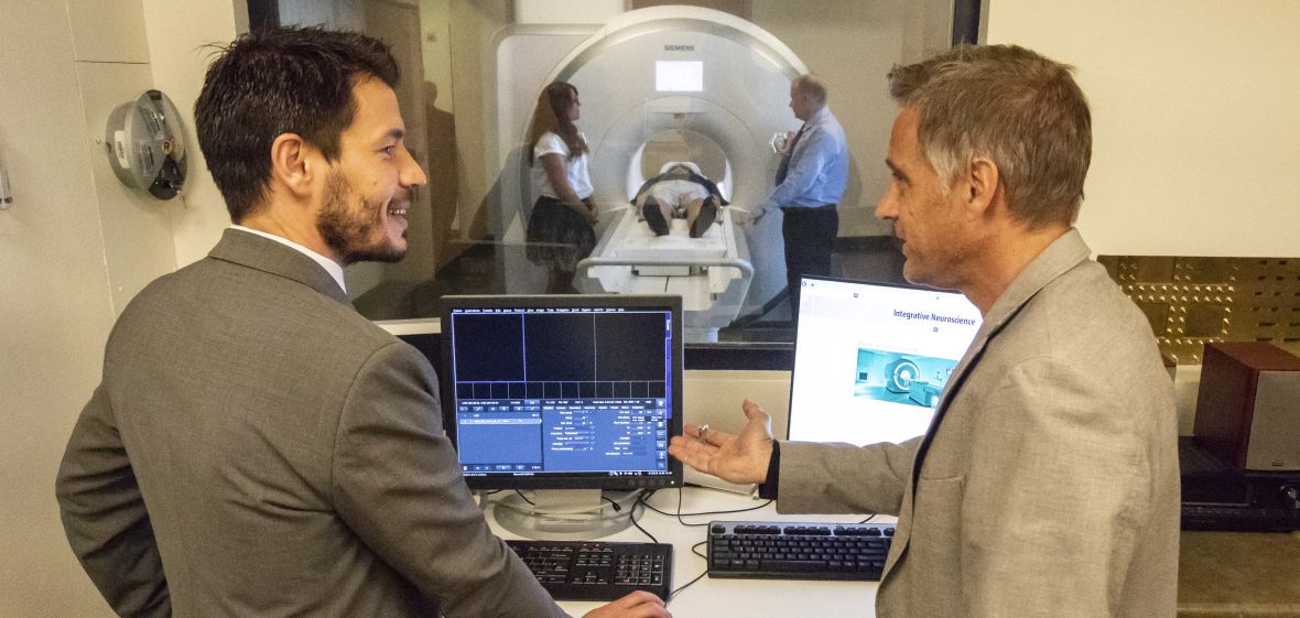 Two people looking at computer image in suite where MRI equipment is operated