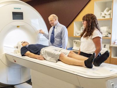 two people prepare another person for an MRI scan