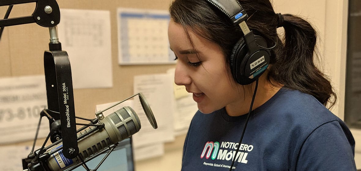 Student speaks into an audio microphone indoors.