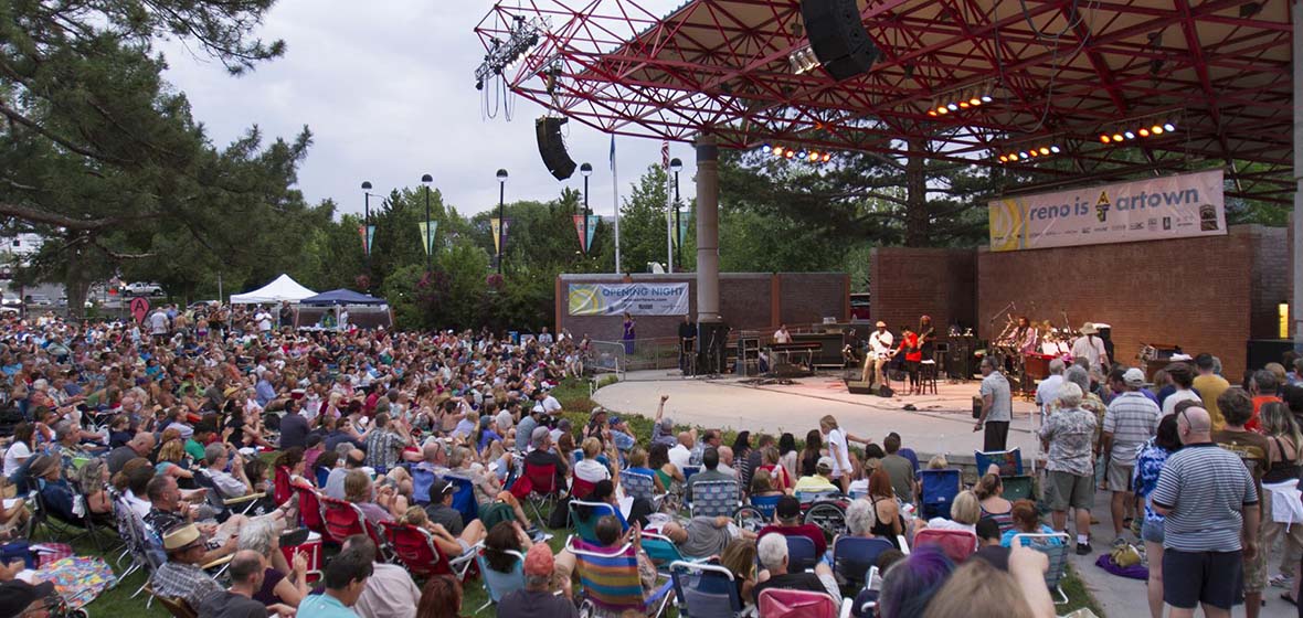 A crowd of people sitting in front of Reno's outdoor Wingfield Park amphitheater