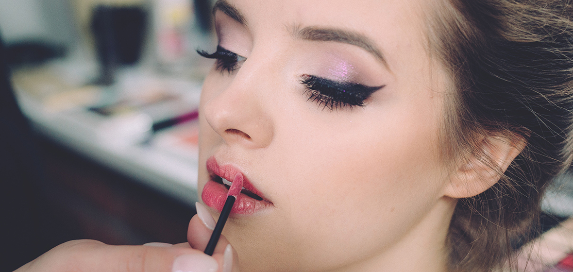 Person with dramatic makeup applying lipstick 