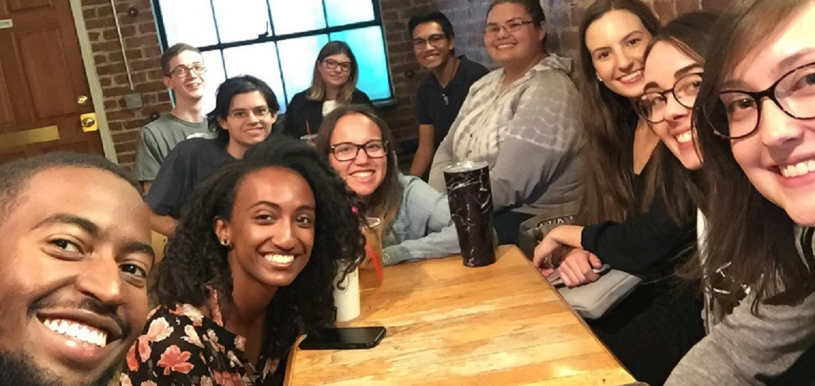 Students from French Club smile and sit around table