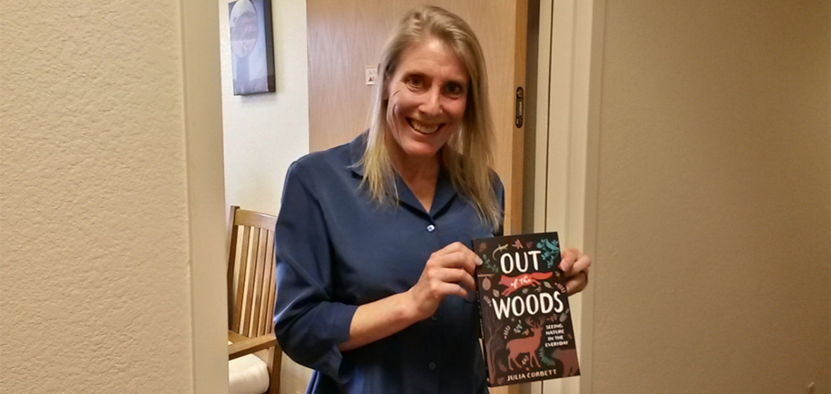 JoAnne Banducci, Business Manager at the University of Nevada Press, holding a copy of Out of the Woods.