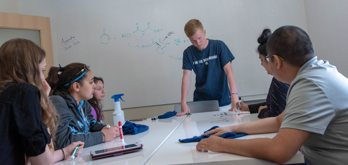 Six students discussing course work around a table during a Nevada PASS session. 