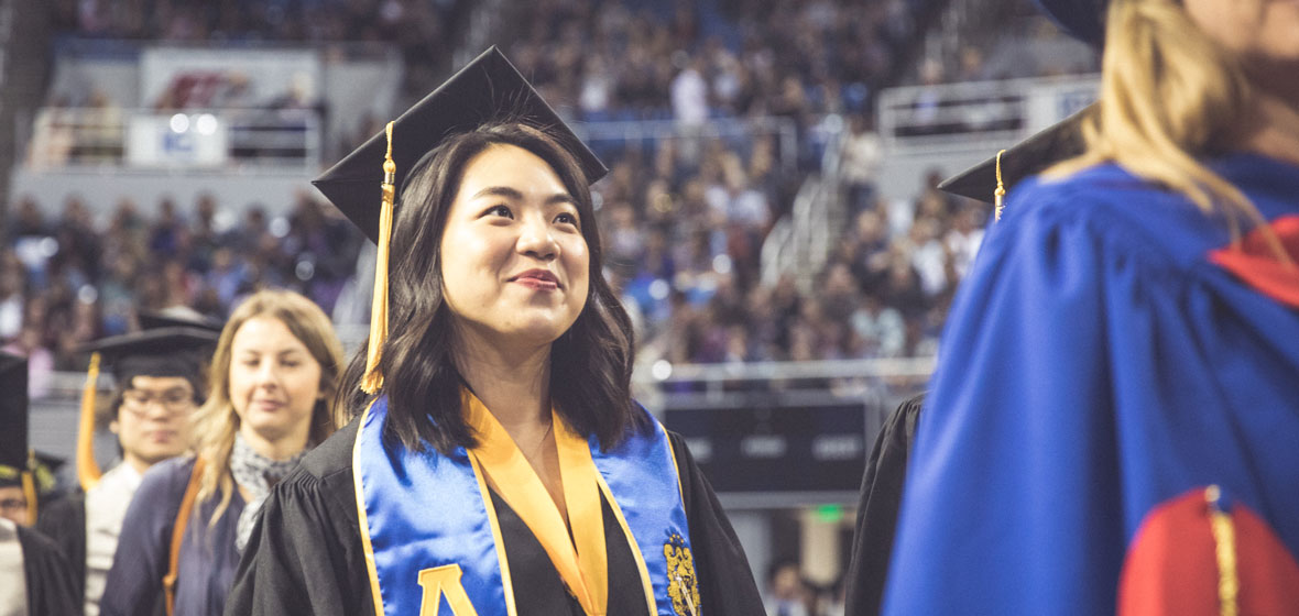 Female student in graduation attire walks towards the stage at the 2019 graduation ceremony.