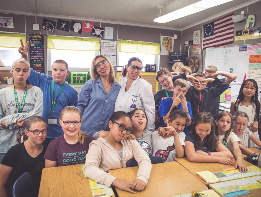 Dr. Voronova and Kimberly Hernandez are surrounded by a class of 5th graders at Jessie Beck Elementary School. Everyone in the photo is making a "goofy face."