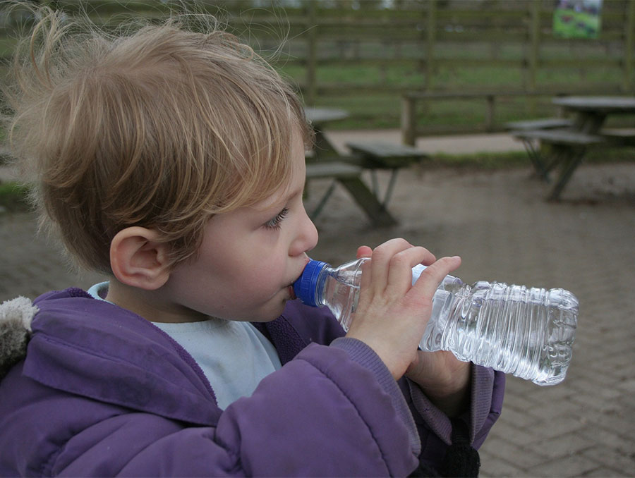A child drinking a bottle of water.
