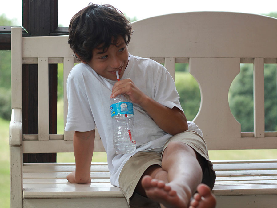 boy drinking water from a bottle with a straw