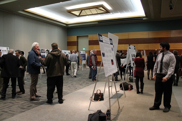 Engineering students and others attending the lecture looking at and presenting research posters