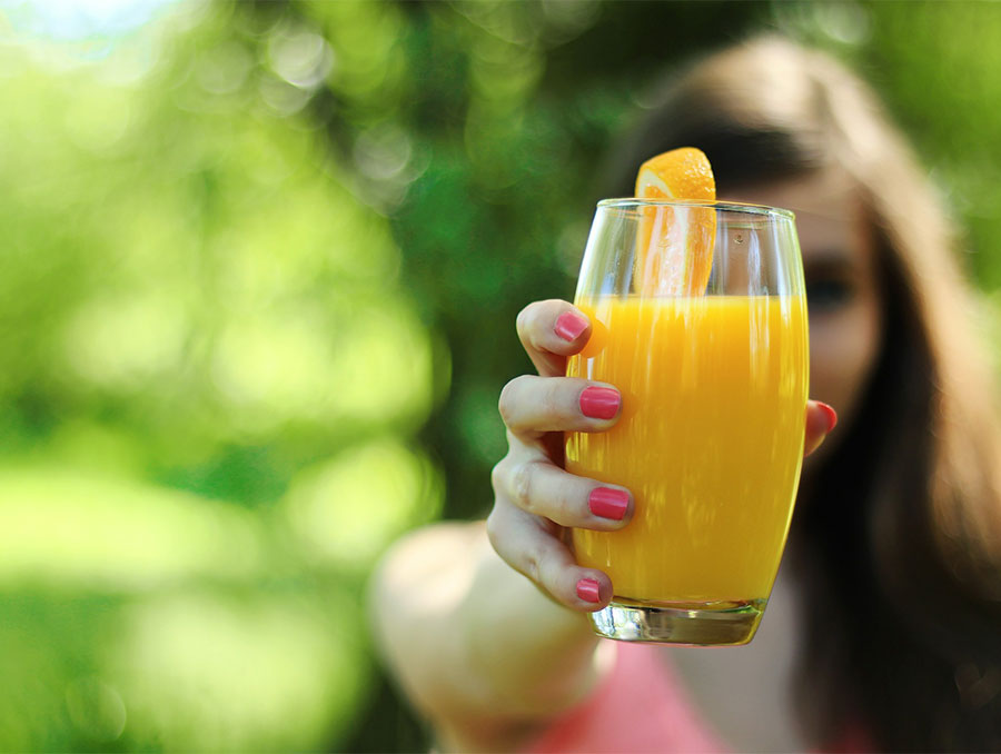 woman holding out a glass of orange juice