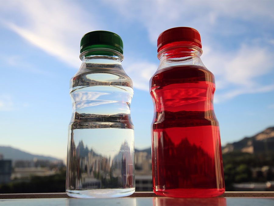 Two bottled drinks, one clear and one red