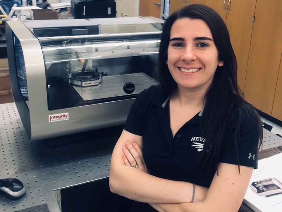 A student stands in the laboratory in front of her research.