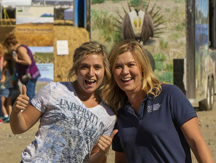 two women at field day giving a thumbs-up