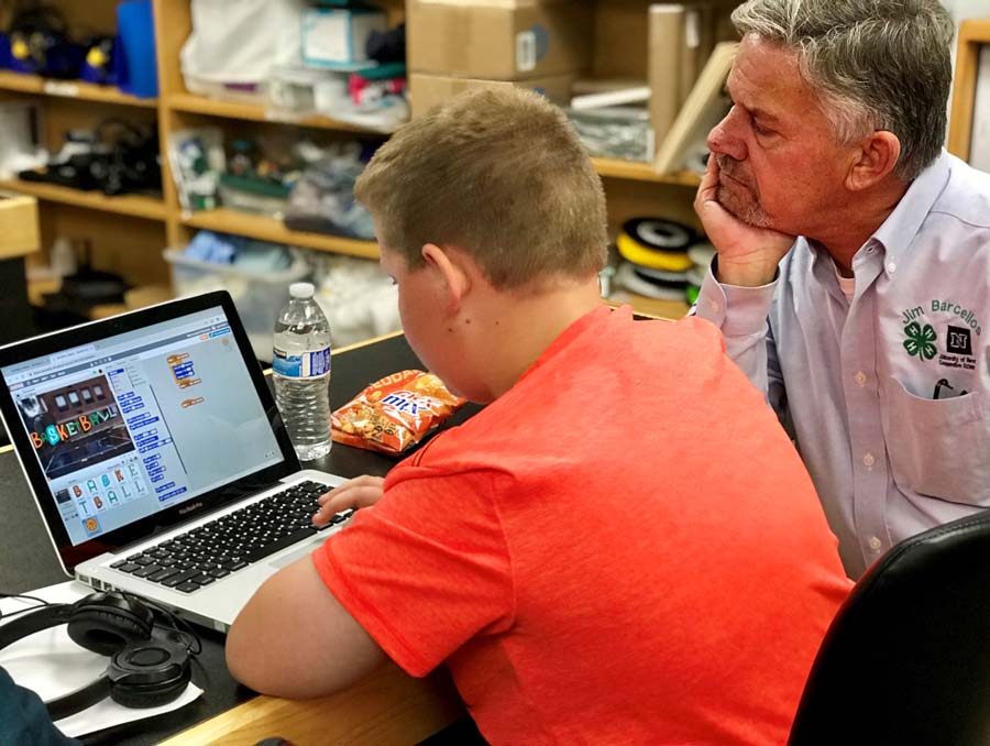 Jim Barcellos helps a boy with last year’s 4-H National Science Day challenge, Code Your World