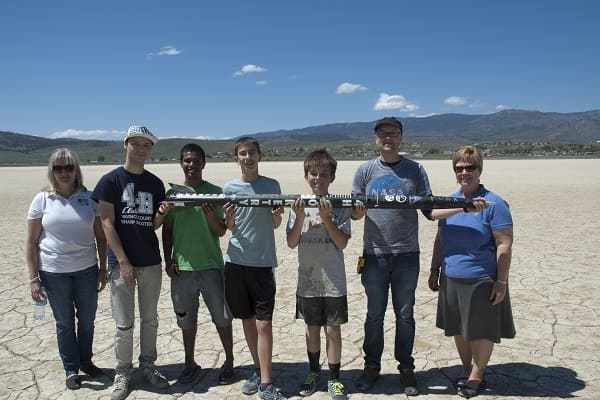 The 4-H High Powered Rocket Club holding a model rocket on a dry lake bed