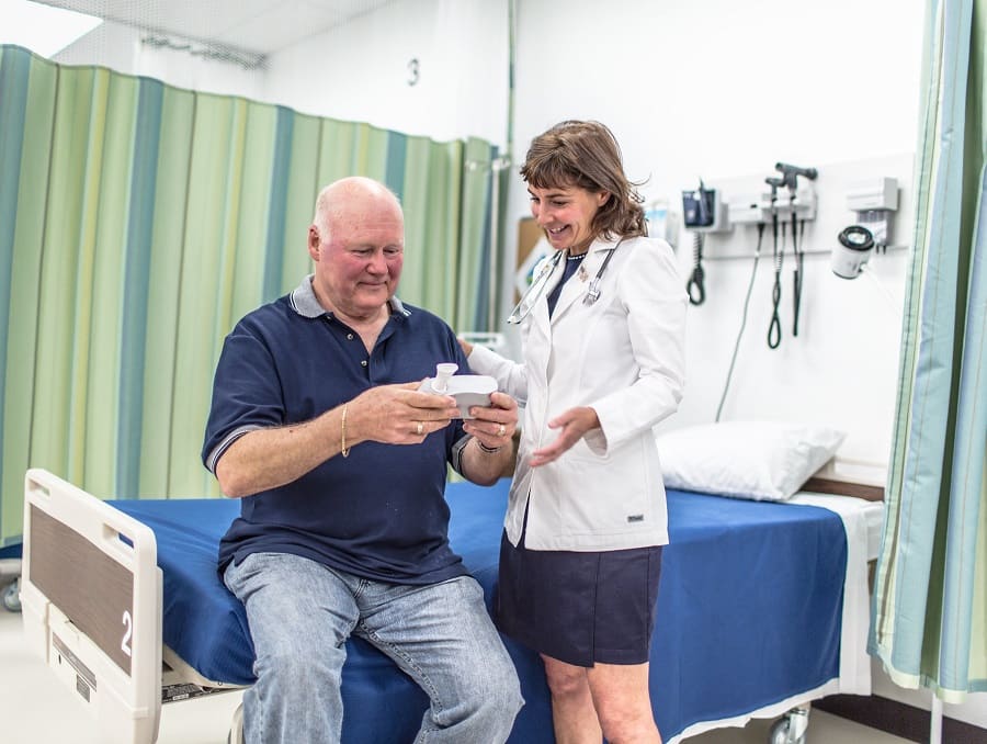 A doctor works with a patient who is holding a medical device