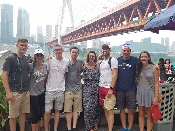 Engineering exchange students smiling in front of a large bridge upon arriving in China