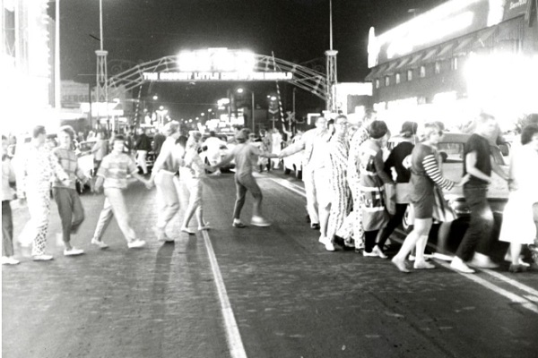 Students in the Pajama Parade walking across Virginia Street underneath the Reno Arch at night during Homecoming activities.