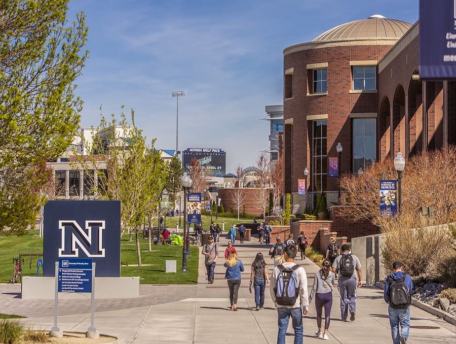 Students walk on campus between the University N statue and the Knowledge Center building.