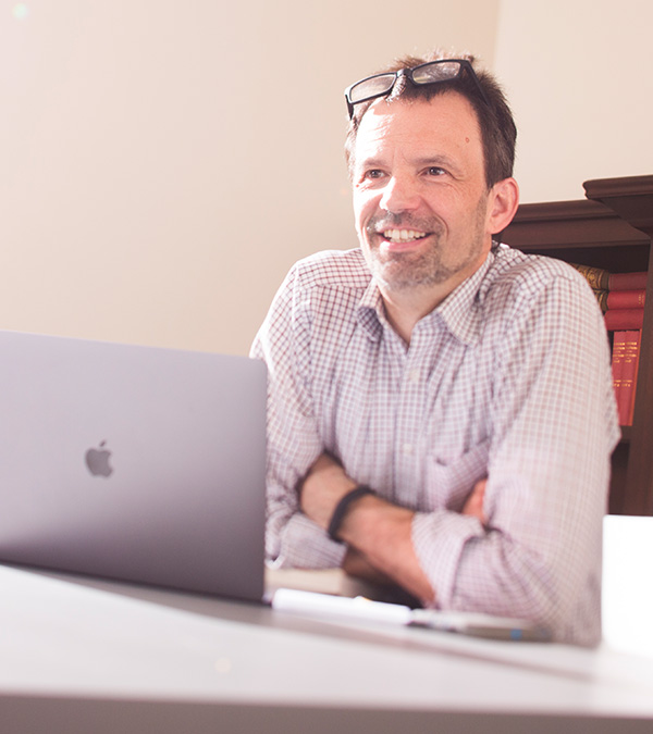 University of Nevada, Reno social psychologist Markus Kemmelmeier sitting at a laptop in an office.