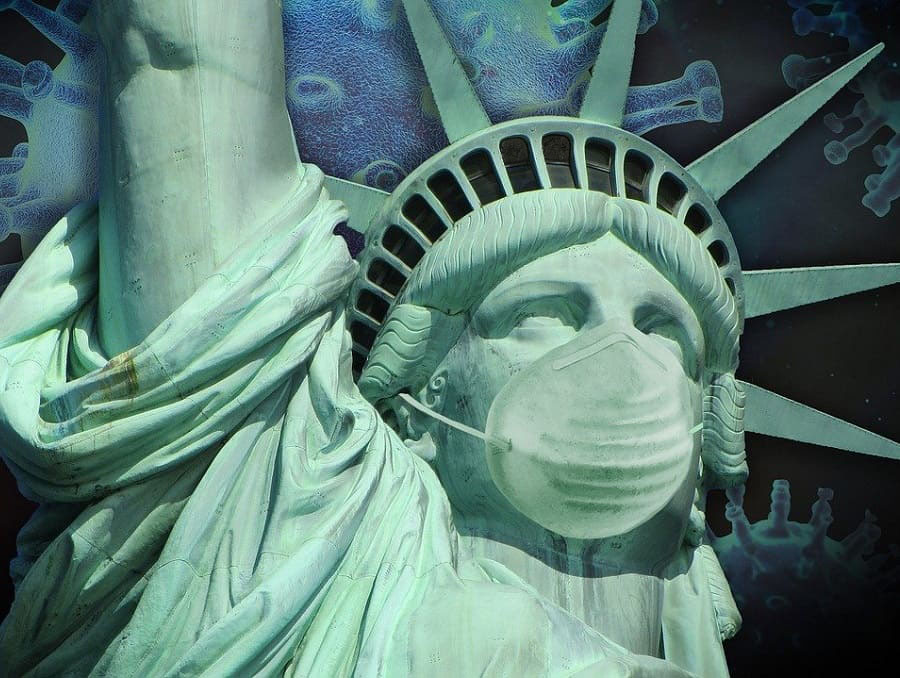 An image of the Statue of Liberty wearing a face mask with coronavirus illustrations in the background