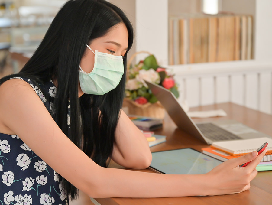 Teacher wearing a mask while looking at a cell phone.