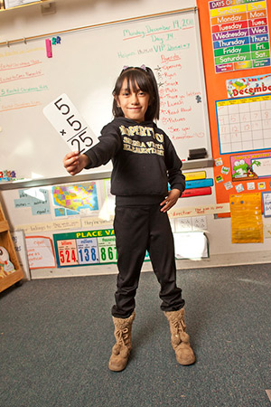 Young student holding multiplication flash card