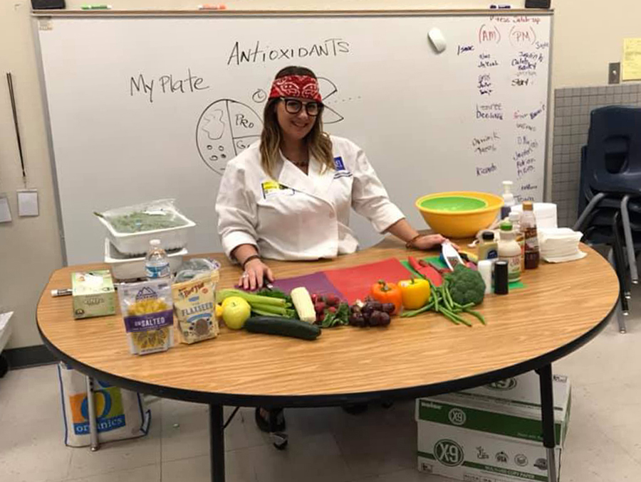 Susan McClain standing behind a table covered with fresh ingredients and cutting boards