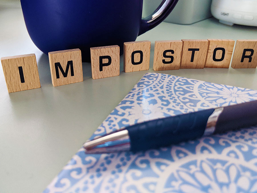 Pen and block letters spelling "impostor" on a table